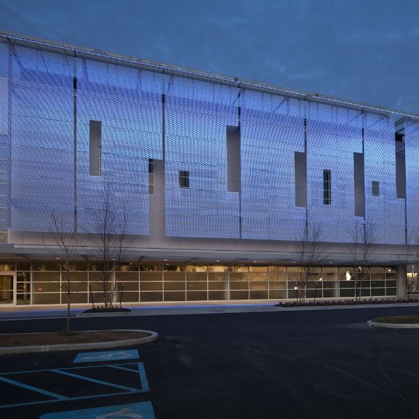 Expanded metal facade shines blue light at night.