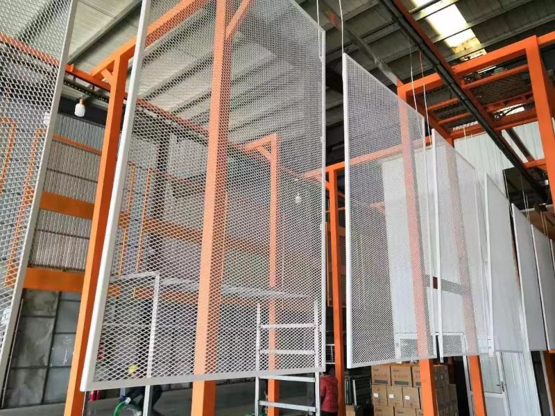 White expanded metal sheets are hanging on the orange steel frame.