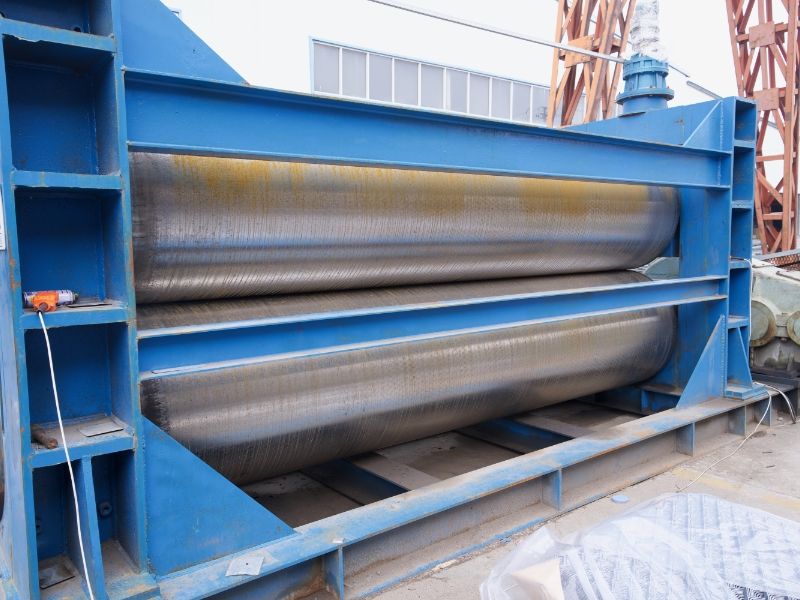 A large expanded metal flattening machine is placed on the ground.